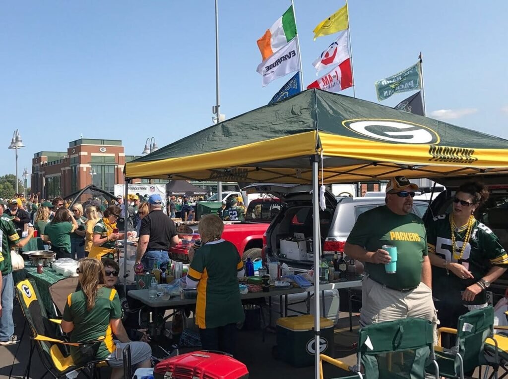 Tailgating at Lambeau Field: The Ultimate 2025 Green Bay Stadium Pre-Game Experience Guide 8 A group of football fans tailgating with food and drinks near Lambeau Field stadium on a sunny day.