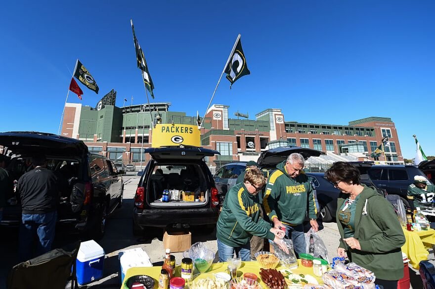 Tailgating at Lambeau Field: The Ultimate 2025 Green Bay Stadium Pre-Game Experience Guide 2 Fans tailgating outside Lambeau Field, wearing Packers gear, grilling food, and socializing before a football game.
